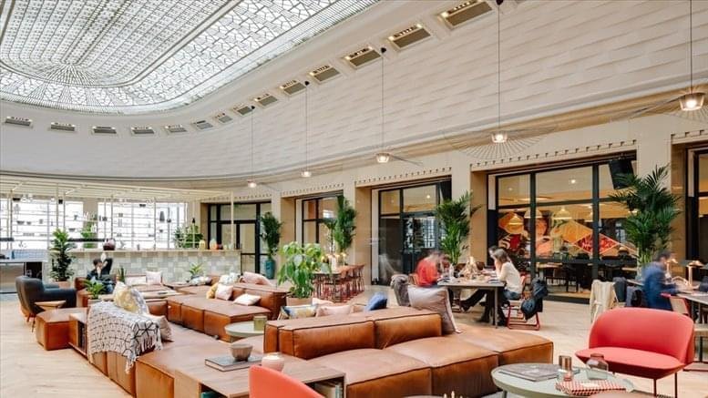 Spacious communal lounge at 104 bld Haussman, Paris featuring leather sofas under a large decorative glass ceiling.