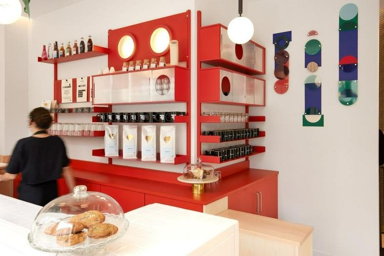 Colorful cafe counter at 11 Rue Beaurepaire, Paris with vibrant red shelving and pastry display.