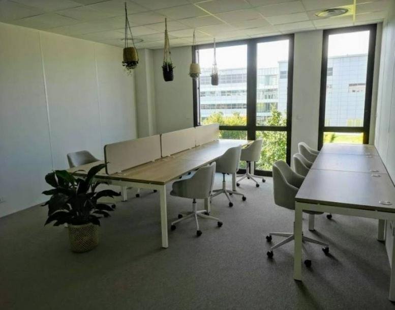 Open-plan workspace with multiple desks and large windows at 13 Rue Pierre-Gilles de Gennes.