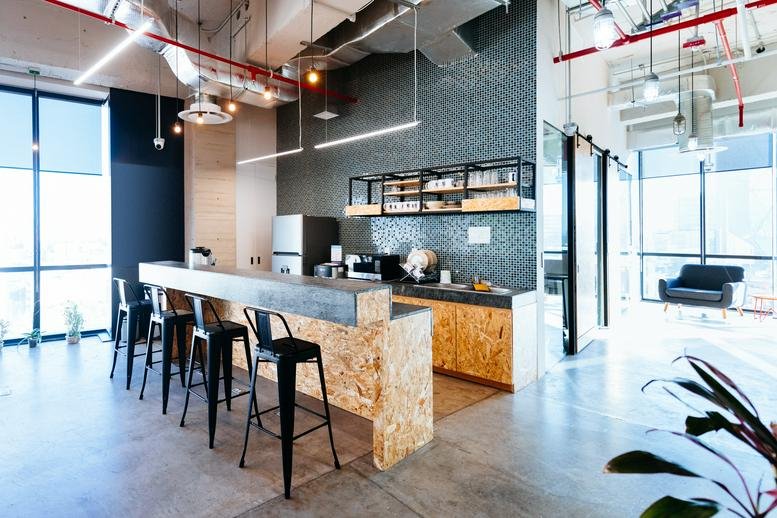 Industrial-style kitchen and breakout area at 15 Rue de Vanves with a modern breakfast bar and stools.