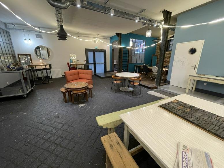 Spacious communal lounge with an orange sectional sofa, cafe tables, and string lighting.