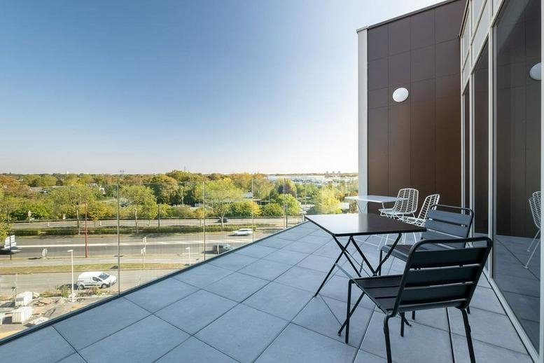 Private balcony with outdoor seating and a wide view over trees and the city at 165 avenue de la Marne.