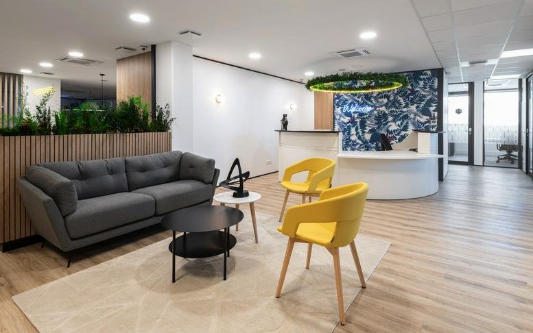 Modern lobby with a white curved reception desk and vibrant yellow chairs.