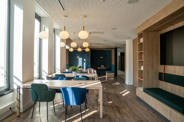 Spacious communal lounge at 17 Rue Saint-Jean, Nancy with wooden floors, round pendant lights, and diverse seating.