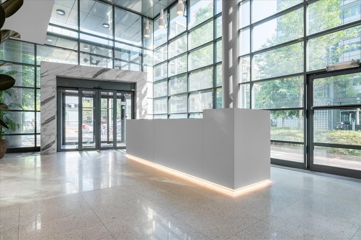 Spacious, sun-drenched lobby at 18-22 Rue Marius Aufan, Levallois-Perret with a sleek white reception desk.