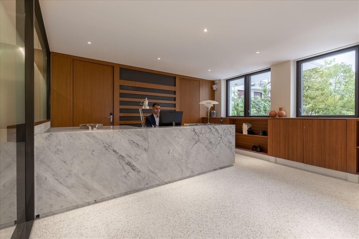 Marble-fronted reception desk in a bright, modern lobby area.