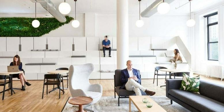 Spacious communal lounge at 19 Rue Poissonnière, 75002 Paris with wooden floors and a green moss wall.