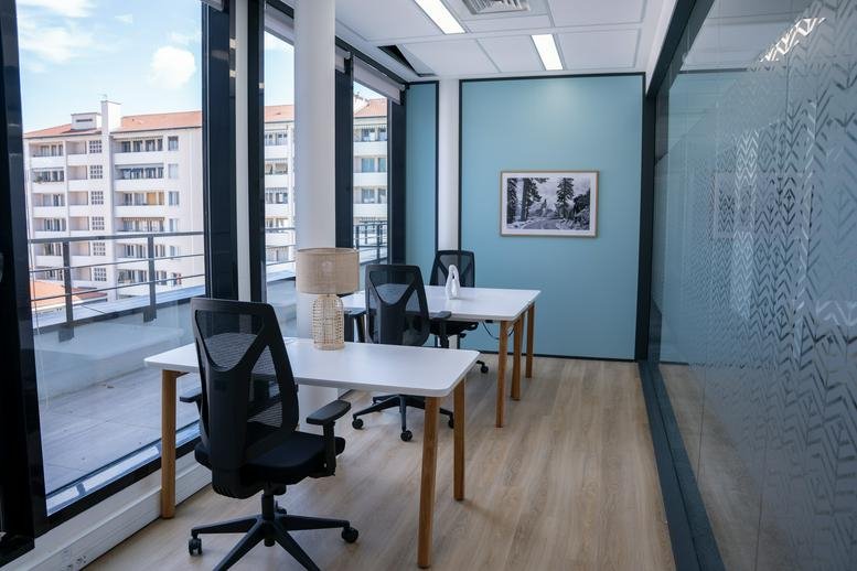 Private office featuring two desks and a view of a terrace through glass walls.
