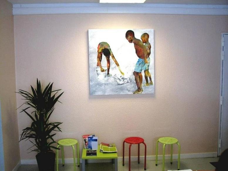 Reception area at 2 allée Giacomo Puccini featuring colorful stools, a potted plant, and beach-themed wall art.