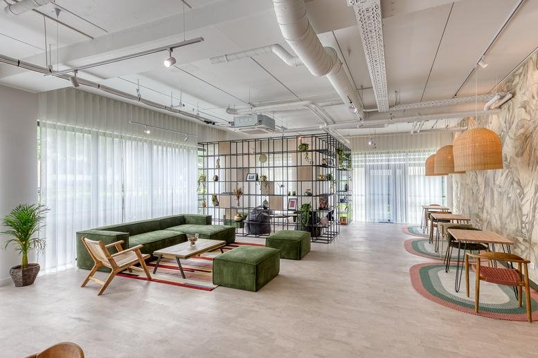 Spacious communal lounge at 2 and 4 Boulevard Michael Faraday with green velvet seating and wooden accents.