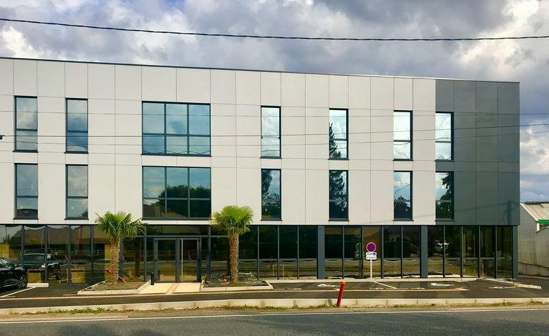Exterior shot of the full multi-story white and grey office building with rows of large windows.