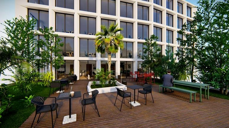 Outdoor terrace with wooden decking, cafe tables, and green trees against the white building facade.
