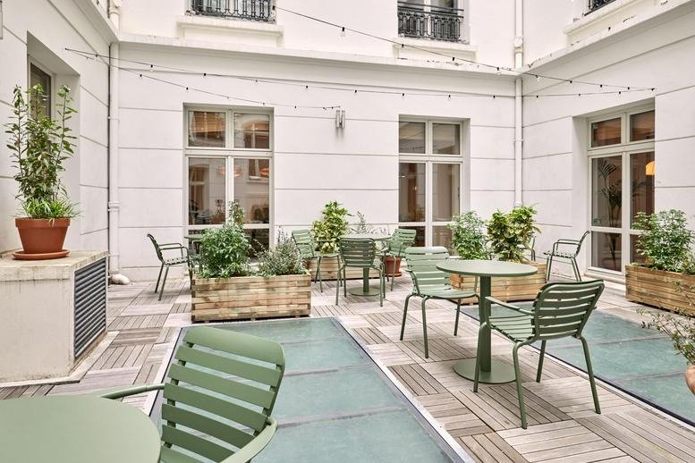 Outdoor terrace at 23 rue de l’Amiral d’Estaing with green metal seating and wooden planters.