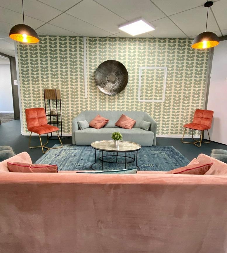 Bright lounge at 24-32 Boulevard Galliéni featuring colorful wallpaper and mid-century modern furniture.