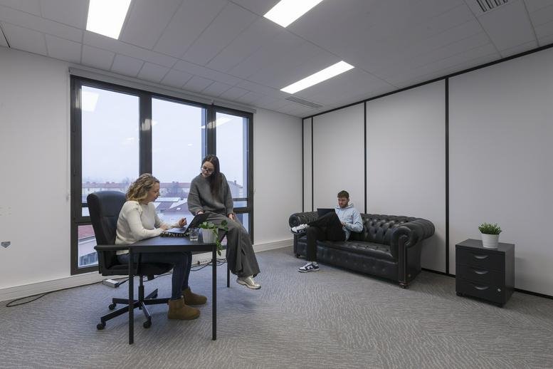 Spacious communal lounge at 24, Rue Laure Diebold with a leather sofa and large windows.