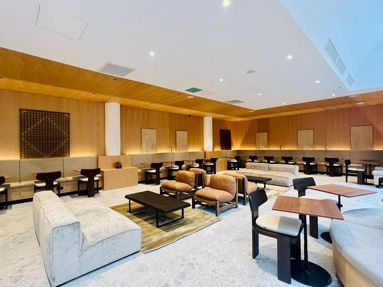 Spacious reception lounge at 26 Rue de Montholon with designer armchairs and warm wood accents.