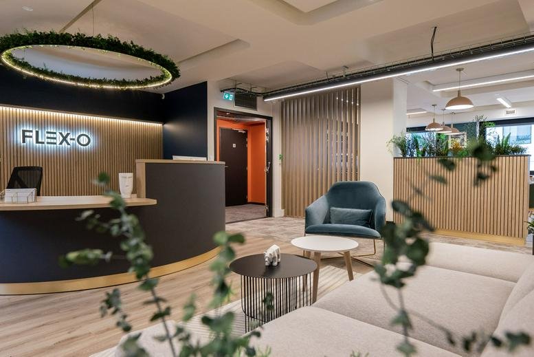 Reception area at 3 rue de Genève with a curved desk, lounge seating, and hanging greenery.