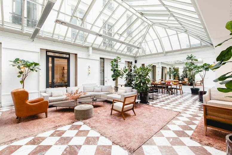 Spacious glass-roofed atrium at 3 rue de Stockholm, Paris with lounge seating.