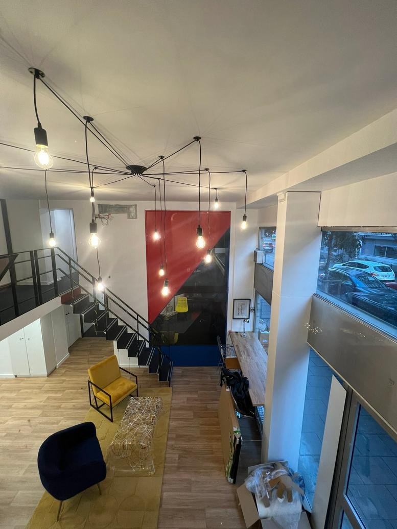 Spacious two-level lounge at 30 Avenue Félix Viallet featuring a spider-style light fixture and yellow armchairs.