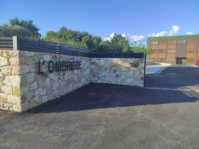 Exterior signage for L'Ombriere on a stone wall entrance.