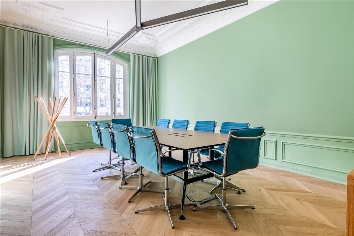 Spacious meeting room at 32-34 Avenue Kleber featuring light green walls and blue designer chairs.