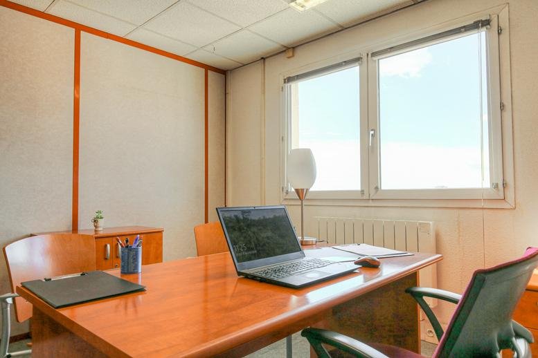Spacious private office at 320 Avenue Berthelot featuring a wooden desk and large windows.
