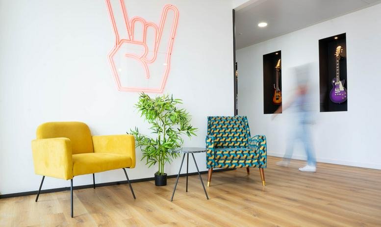 Colorful lobby at 4 chemin de l’arenas with rock sign wall art and modern armchairs.