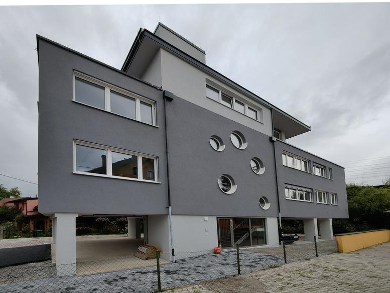 Exterior view of the grey and white building at 4, Hartlebengasse, Salzburg featuring unique circular windows.