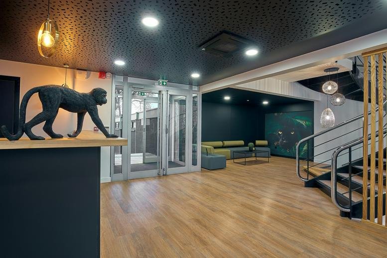 Bright lobby at 4 rue de l’Industrie, Mundolsheim, Bas-Rhin featuring a monkey sculpture and modern staircase.