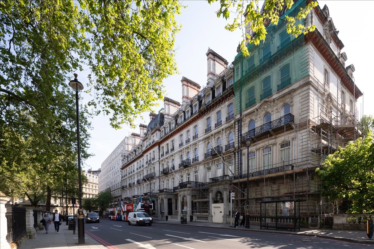Wide street view of the historic white facade of 42-44 Grosvenor Gardens lined with trees.