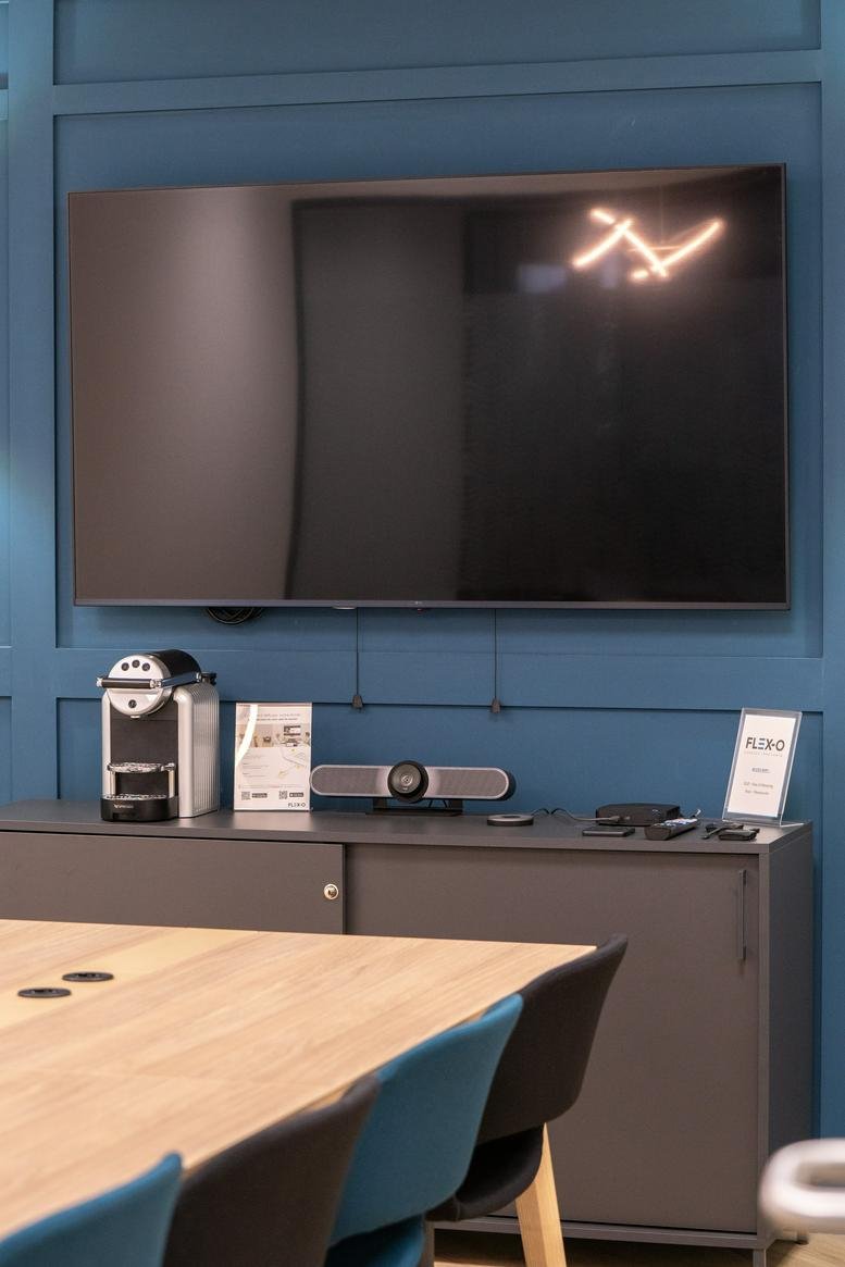 Modern conference room featuring a large flat-screen TV mounted on a blue wood-paneled wall.