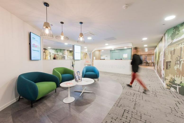 Spacious reception area at 46bis avenue du Maine, Paris with colorful armchairs and modern pendant lighting.