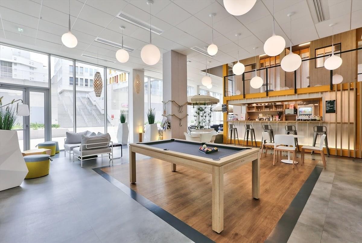 Spacious common area at 48 Quai du Lazaret with a pool table, modern globe pendant lights, and floor-to-ceiling windows.