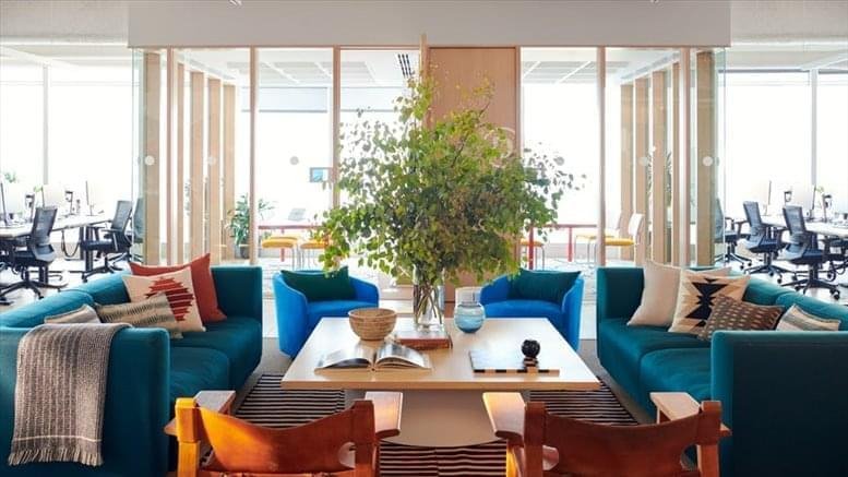Spacious lounge at 5 Rue des Italiens, Paris with teal sofas and large potted plants.