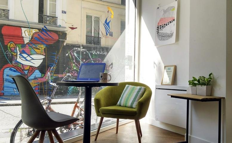 Sunny workstation at 54 rue Greneta, Paris with a street art view and lime green armchair.