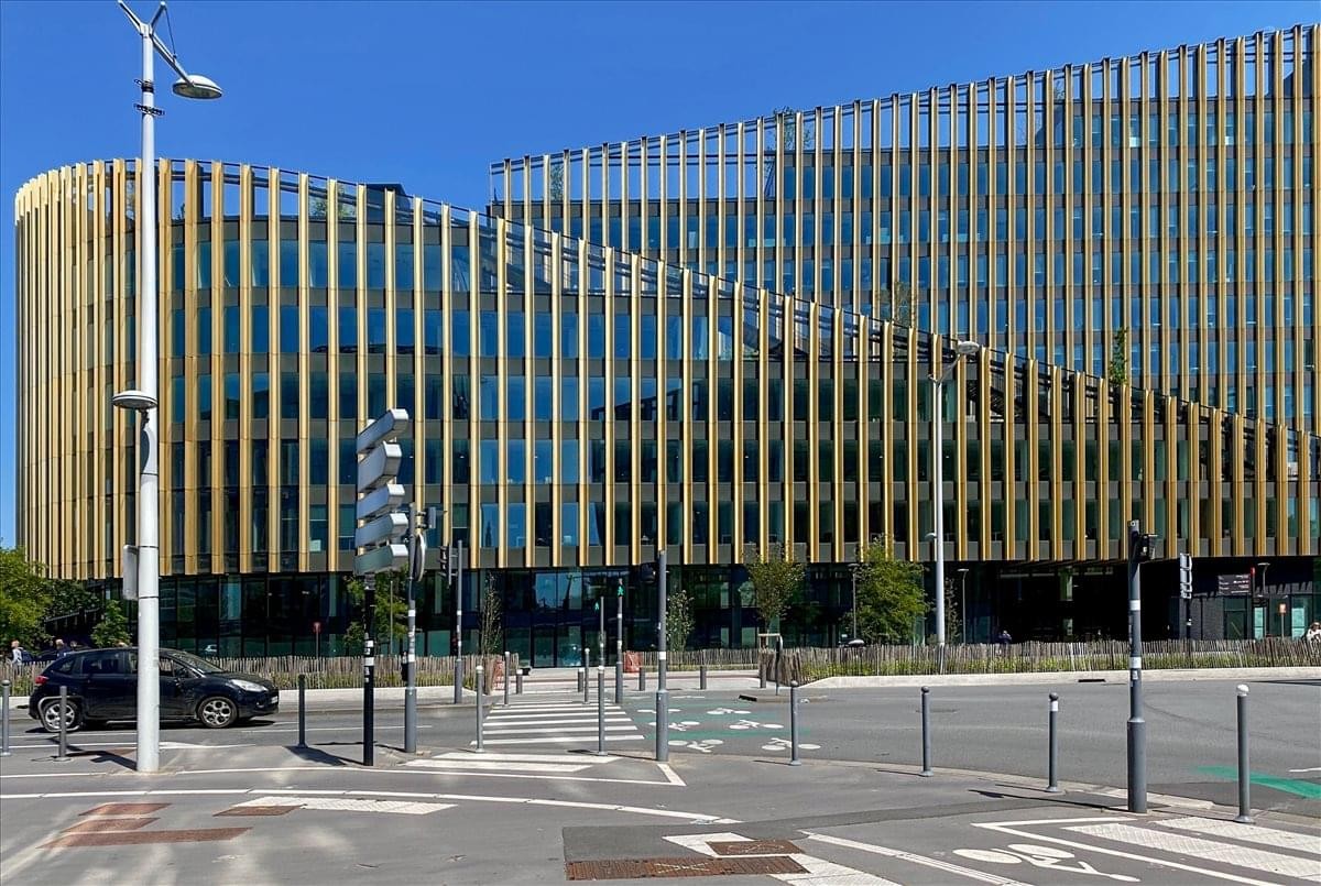 Exterior view of the modern glass and gold-finned building at 594 Avenue Willy Brandt.