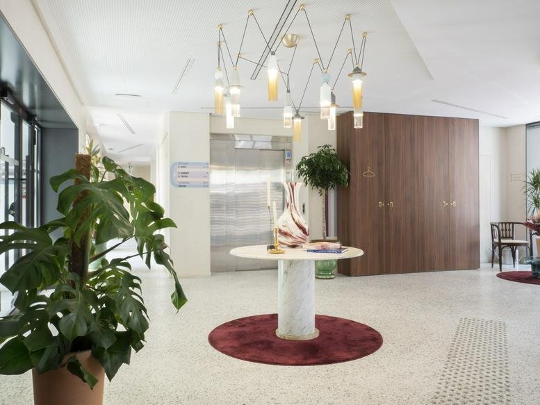Lobby at 7/9 Rue Jadin, Paris featuring a marble table, designer lighting, and wood paneled walls.