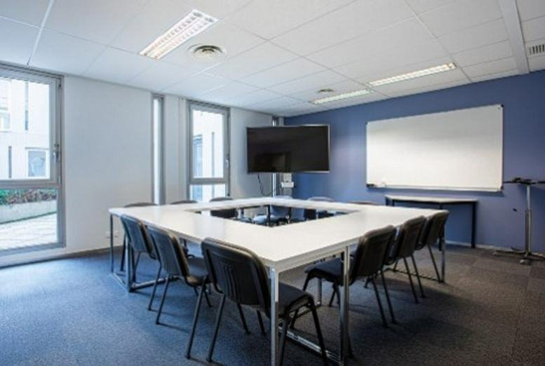 Modern meeting room at 8 Rue Des Frères Caudron with a square conference table and blue accent wall.