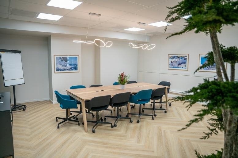 Conference room with a large wooden table and teal upholstered chairs.