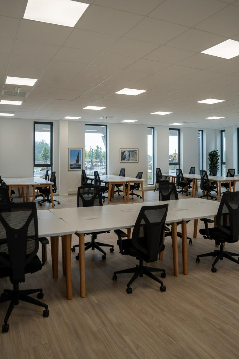 Spacious open-plan workspace at 801 Avenue Des Champs Blancs with wooden desks and modern ergonomic chairs.
