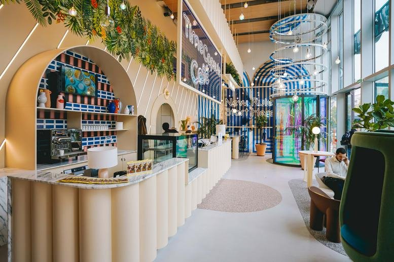 Spacious communal cafe area at 82 Avenue du Maine, Montparnasse Gaite, Paris featuring arched shelves and plants.