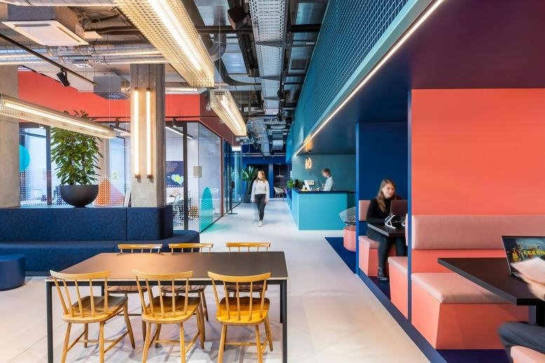 Spacious communal lounge and workspace at Am Tabor 36, Vienna, Austria with vibrant blue and coral feature walls.