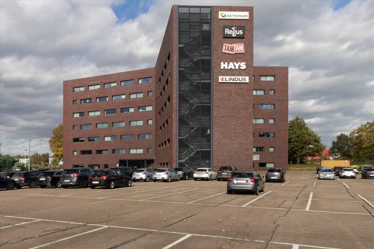 Exterior view of the brick facade building at Atealaan 34, Herentals with large parking area.