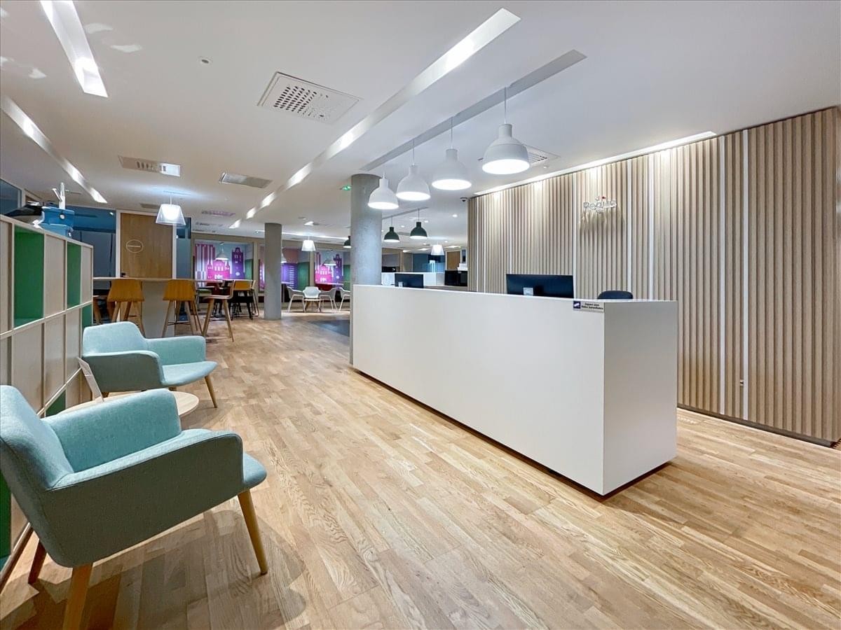 Modern reception area at Avenue Pierre-George Latecoère with a white desk and light blue armchairs.