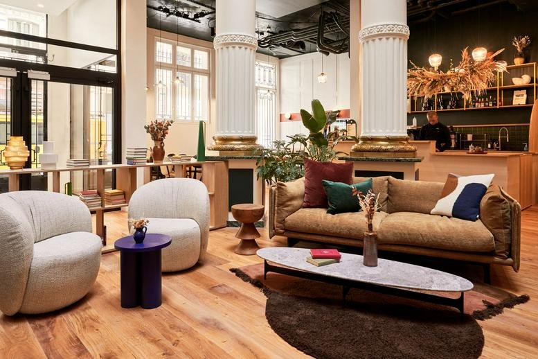 Spacious communal lounge at Bourse-Vivienne, 9 Rue des Filles Saint Thomas with velvet sofas and ornate columns.