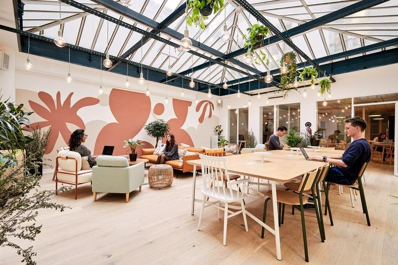 Sun-drenched atrium at Cléry, 21 Rue de Cléry, Paris with a glass ceiling, mural, and lounge seating.
