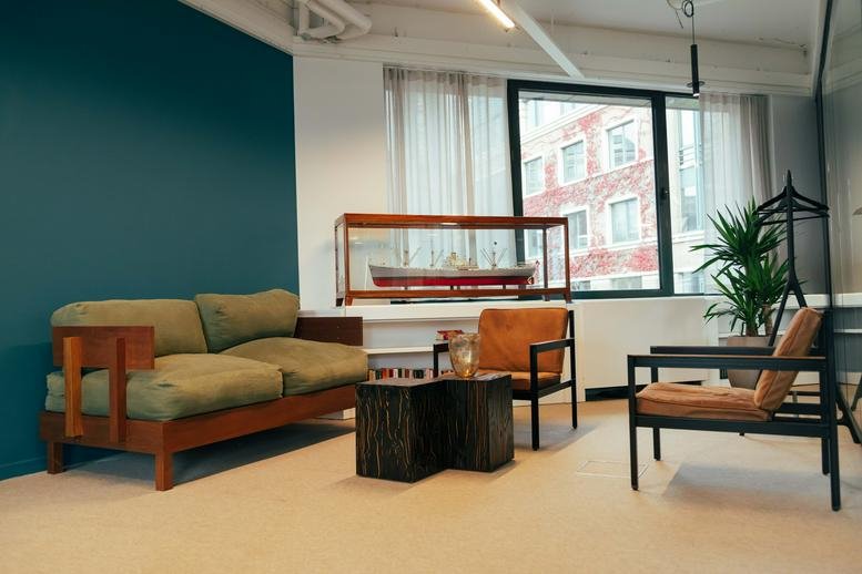 Lounge area at De Gerlachekaai 20, Zuid, Antwerp, Belgium featuring a green sofa and teal feature wall.