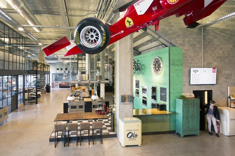 Spacious open lobby at Diamantstraat 8 featuring a suspended red vintage race car.