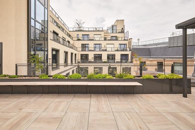 Rooftop terrace with wooden decking and stone planters at Faubourg-Saint-Honoré, 128 Rue du Faubourg Saint Honoré.