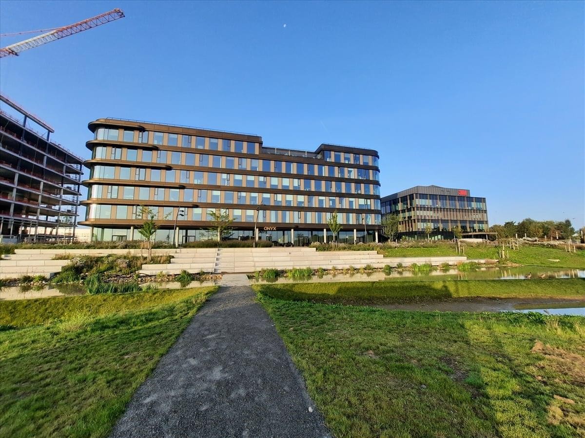 Wide exterior shot of the modern office complex and landscaped grounds under a clear blue sky.